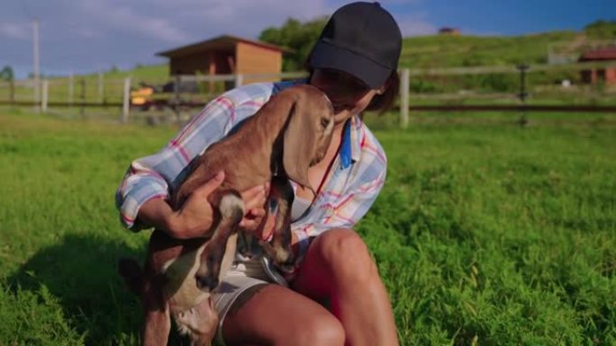 农场游客在畜牧场玩可爱的小山羊，女人抱着小波尔山羊