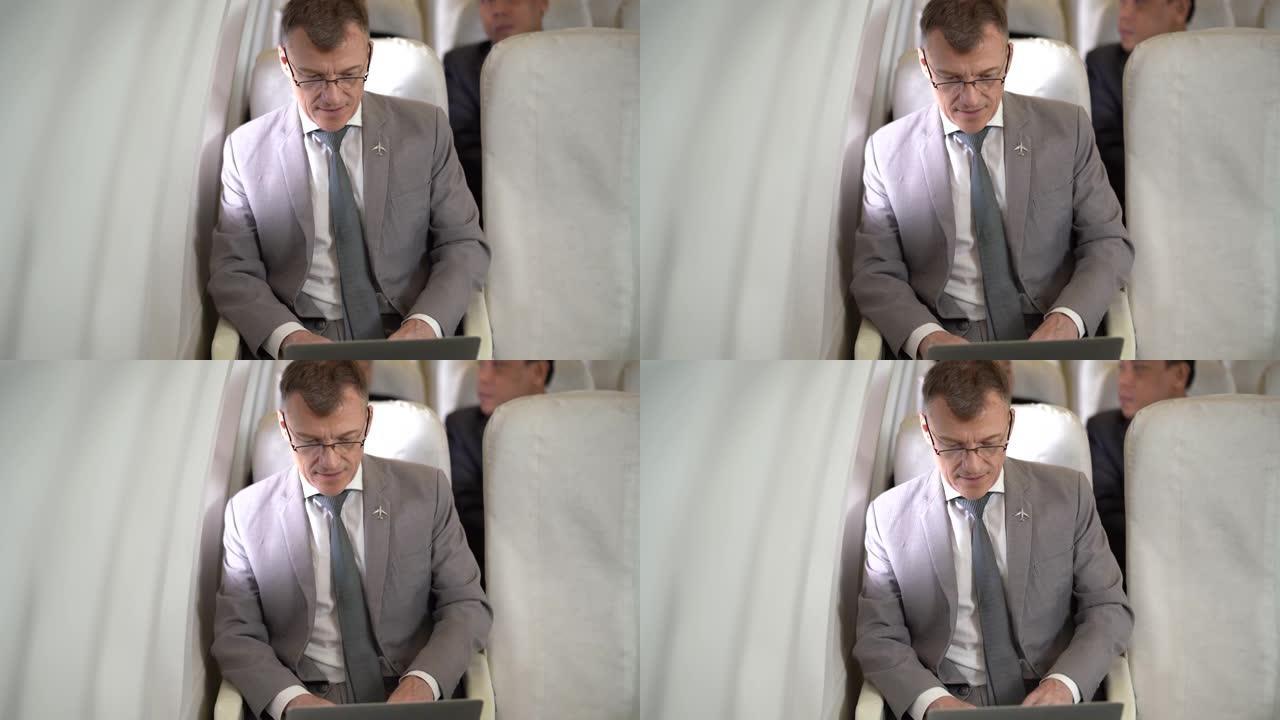 坐在飞机上的笔记本电脑上工作的商人