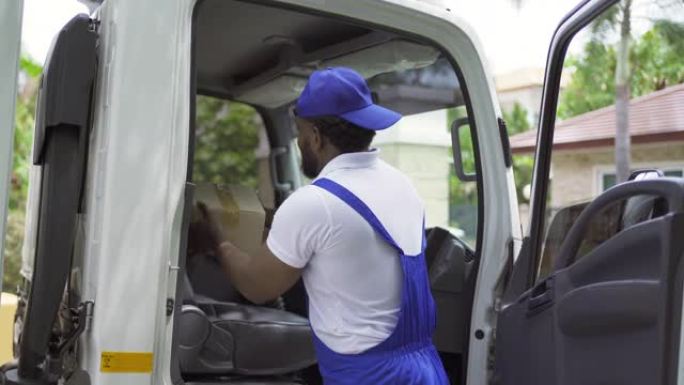 黑人雇员工人带着一辆卡车为顾客搬房子，送制服的箱子。车辆运输。航运和包装业务职业服务公司。人们的生活