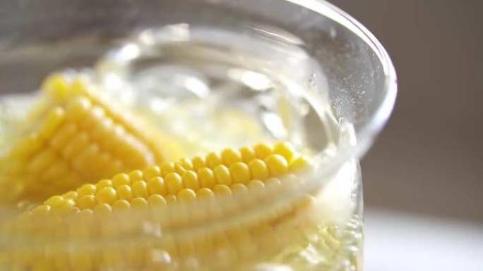 在沸水中成熟的玉米棒。有机黄玉米在玻璃锅里，开水。烹饪
