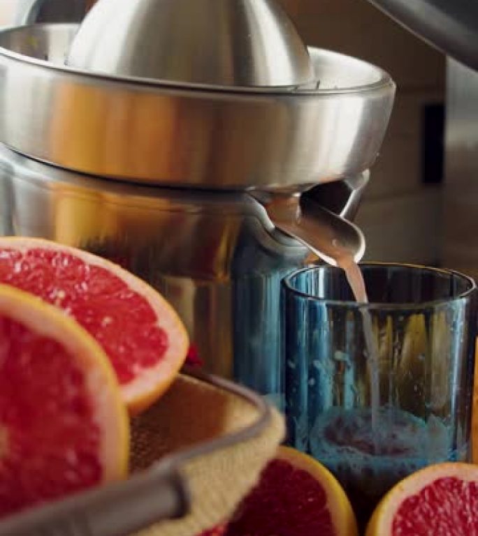 男性的手在榨汁机上挤压葡萄柚汁。特写视图。垂直镜头。