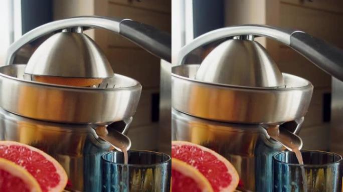 男性的手在榨汁机上挤压葡萄柚汁。特写视图。垂直镜头。