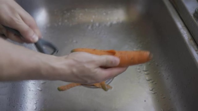 男人的手洗胡萝卜在水槽特写自然光。HLG3, BT.2020