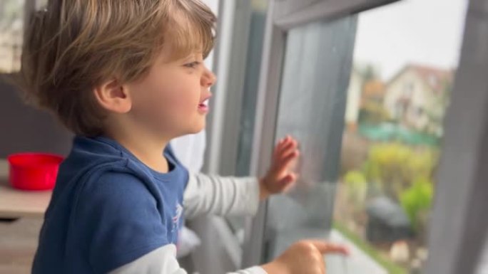 孩子坐在窗边被困在家里。小男孩想出门在外