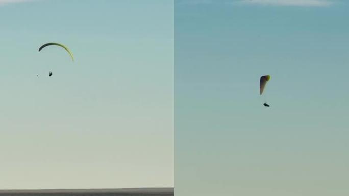 多色滑翔伞在大悬崖沙漠平原上空盘旋飞行