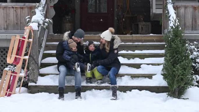 一家人带着两个孩子在下雪的森林里拉着圣诞树