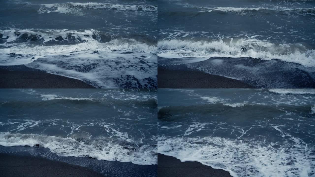 蓝色海潮席卷冰岛海滩。海浪泡沫撞击沙滩自然