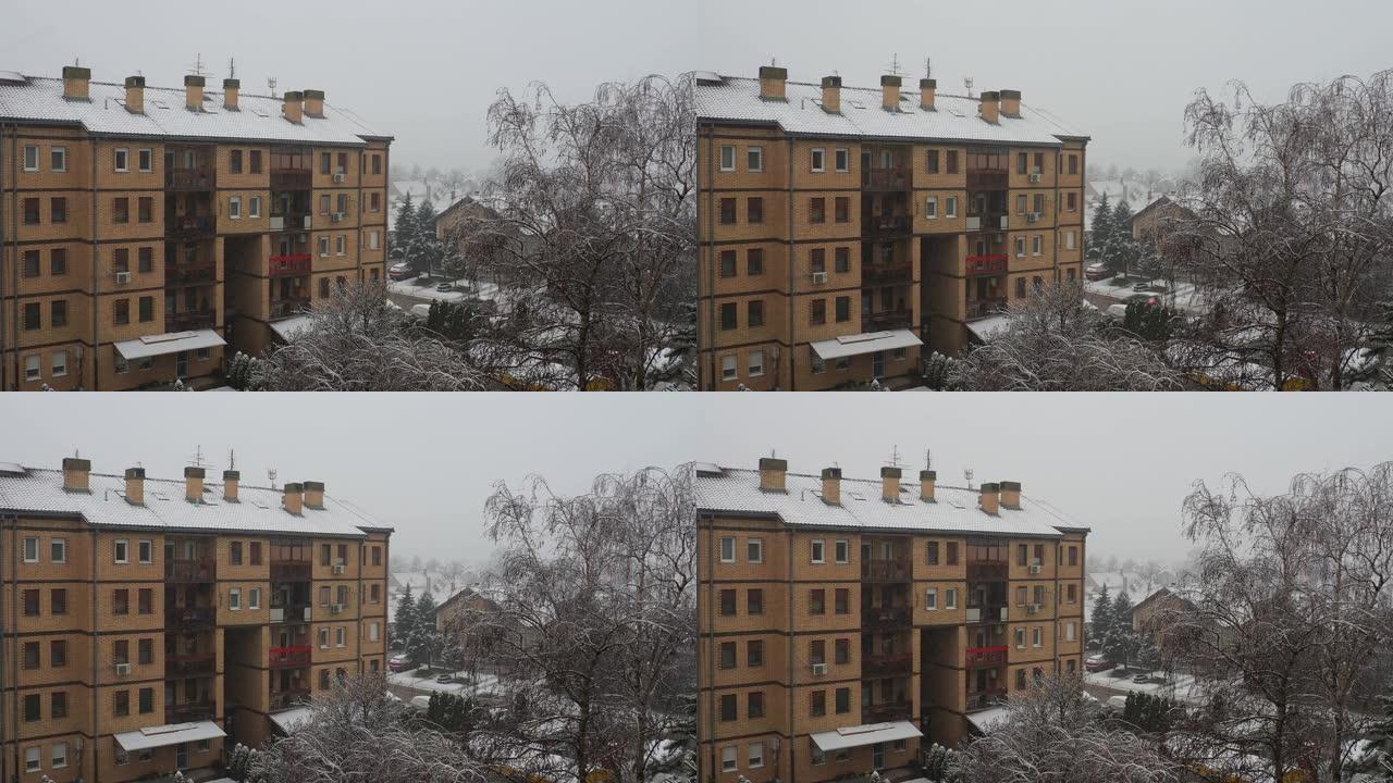 城市降雪。大片白色雪花从多云的天空落下。巴尔干半岛的天气预报。唐楼和树木被雪覆盖。