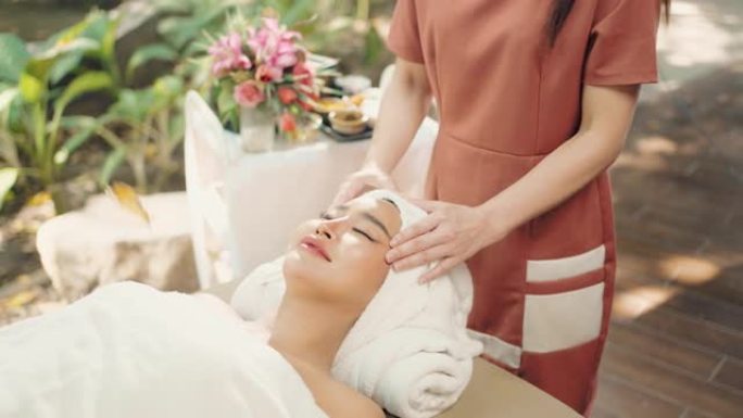 亚洲美丽的女性在水疗中心享受放松的面部护理