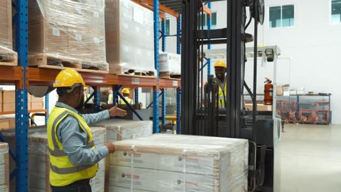 安全磨损的非洲仓库工人正在操作叉车堆垛机来移动包裹堆。