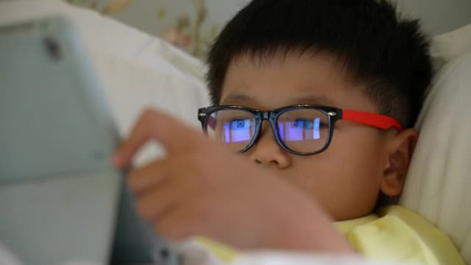 亚洲男孩在数字平板电脑上玩社交媒体。成瘾的概念
