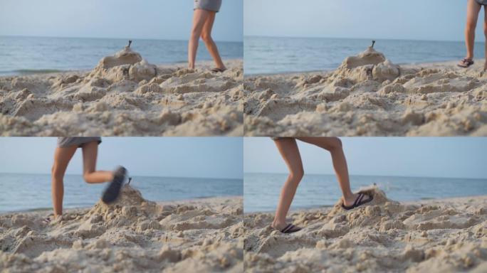 一个男孩用脚践踏了海边的一座沙堡