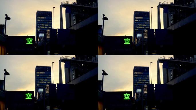 黄昏时的城市建筑，抬头看着空荡荡的停车场标志和高速公路。东京六本木的城市风光