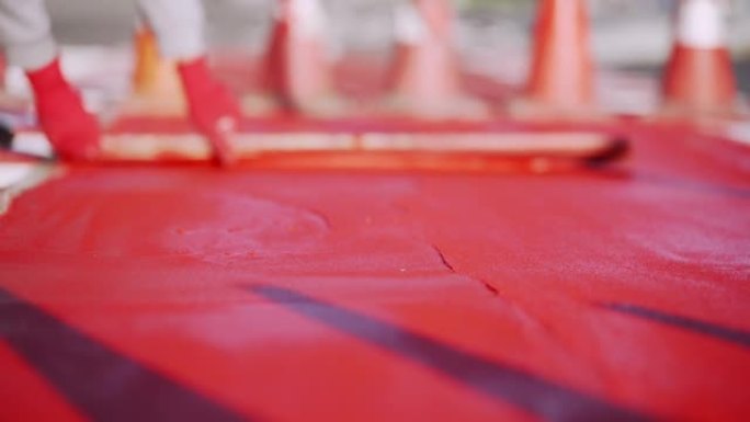 工人使用红色热塑性材料。建设有人行横道和自行车道的道路。