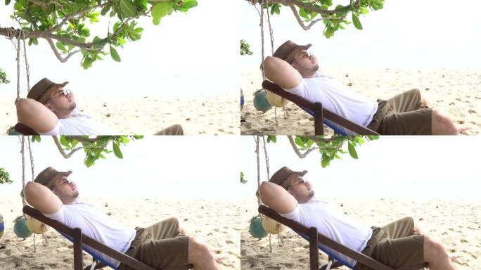 亚洲男子坐在海边的椅子上，夏天放松一下
