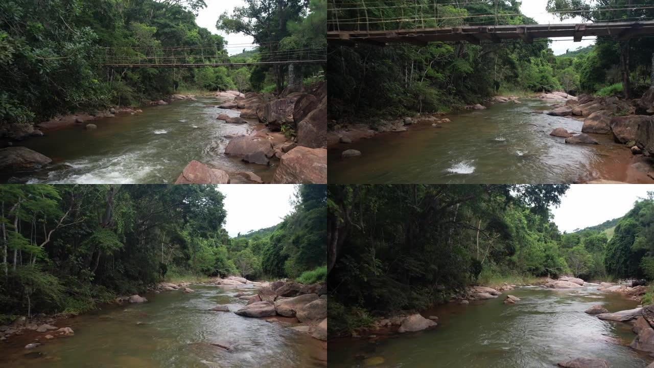在巴西丛林中的一条河之后的人行吊桥下的POV鸟瞰图