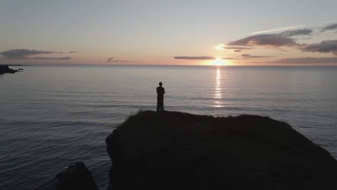 一个男子冥想的特写4k在日落时站在岸边的山顶上