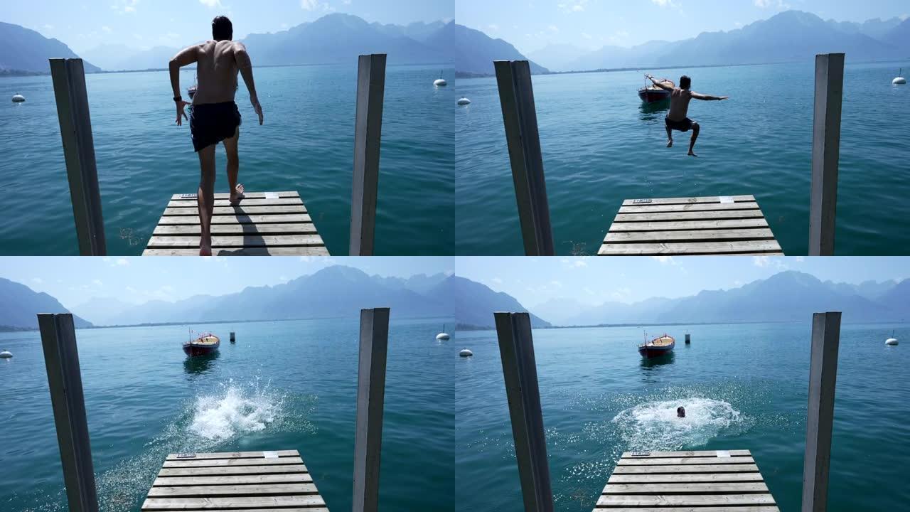 年轻人跑着跳进瑞士湖水，背景是山。木制码头码头