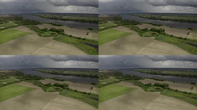 中午的无人机摄影左图——明亮的农田和田野，宽阔的河流和乌云在背景中。波美拉尼亚，波兰，欧洲