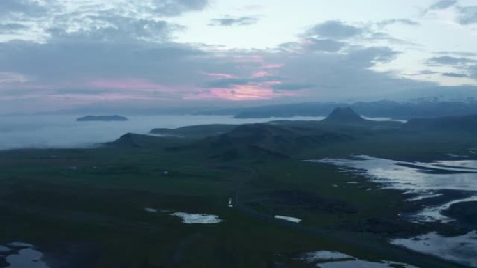 日出时呼吸的空中全景镜头拍摄北欧风景。平地雾之上突出的山丘。冰岛