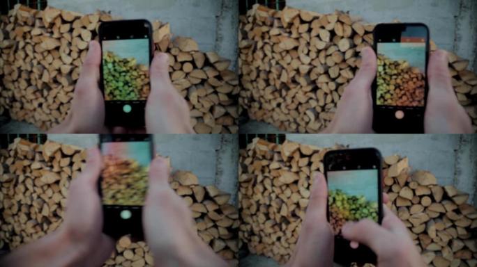 一个人用高清手机拍摄堆积的树木木材照片的特写镜头