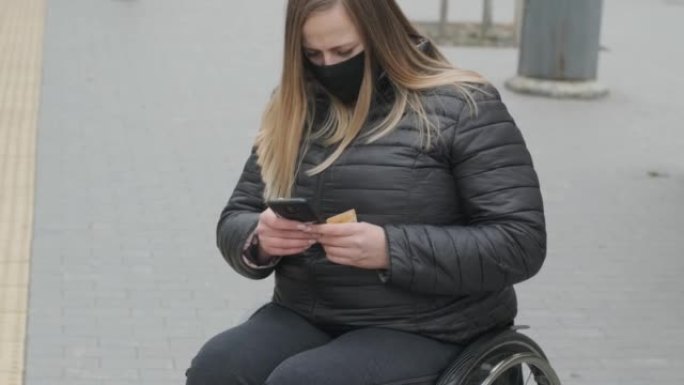有身体残疾的妇女使用轮椅，带着手机和防护口罩。