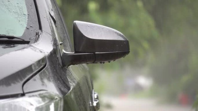 雨滴在灰色的汽车上。车窗上的雨和滴水