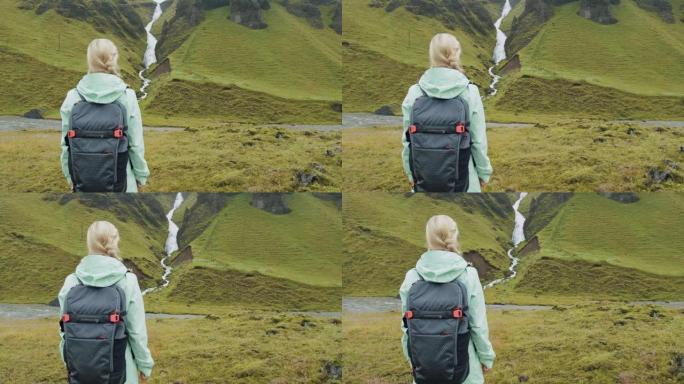 在冰岛南部海岸Fjadrargljufur附近的冰岛瀑布前背着背包的女游客