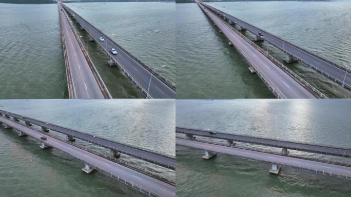 在泰国宋卡府，沿着横跨湖的桥梁行驶的汽车和车辆的空中无人机拍摄