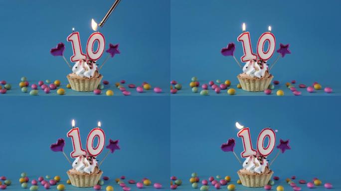 给一个10岁的孩子生日快乐，一个带有蜡烛的生日蛋糕和蓝色背景上的生日装饰品。点燃并熄灭纸杯蛋糕上的节