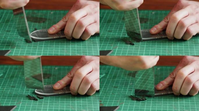 男子裁缝切割人造革与模板特写。工匠在工作场所的桌子上雕刻牛皮，制作由真皮动物皮革制成的手工产品。专业