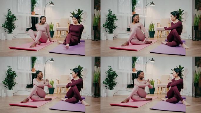 年轻灵活的亚洲和非裔美国女性朋友旋转身体，在家练习瑜伽，打手势namaste