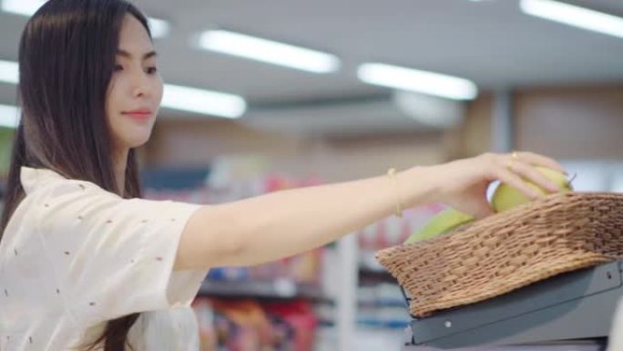 年轻亚洲妇女在杂货店购买新鲜水果和蔬菜或消费品