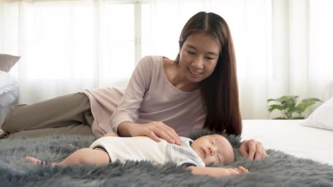 4K 50fps，新生儿，2个月大的亚洲宝宝在地毯上睡觉。他妈妈哄他温暖地睡在你身边