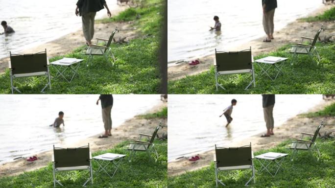 男孩在海滩附近游泳，同时与父亲举行海滩派对。