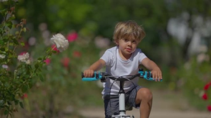 一个小男孩在公园外面骑自行车，孩子骑自行车