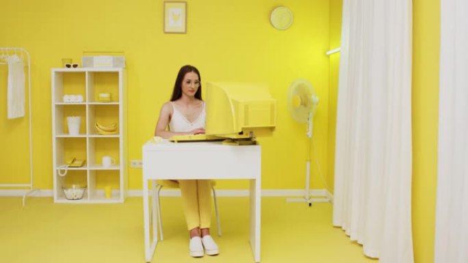 年轻女子在旧黄色PC上工作