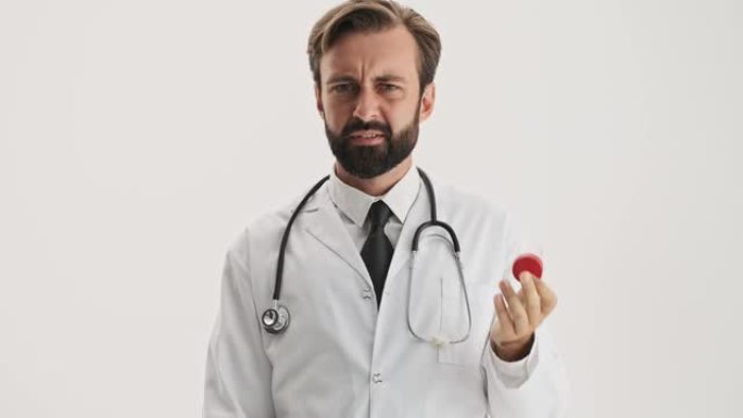 困惑的男人医生用听诊器看着药瓶，用手打手势