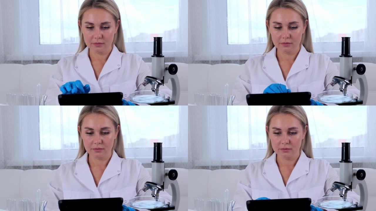 女科学家研究化学家穿着医疗服和防护手套，用平板电脑和显微镜在实验室进行研究