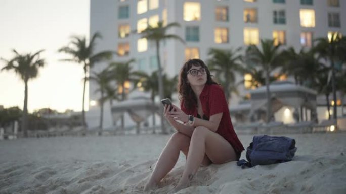 女人坐在酒店附近的海滩上发短信