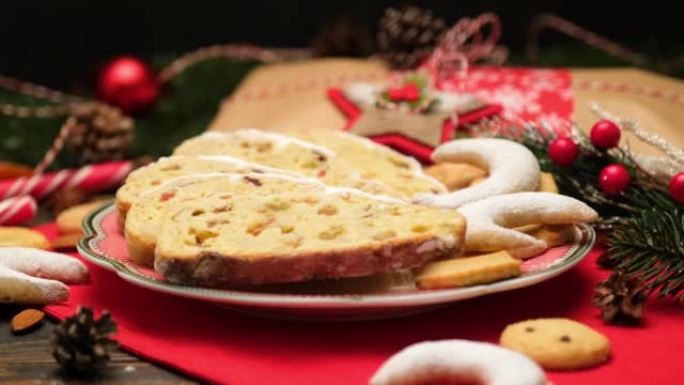 切片传统圣诞蛋糕，带杏仁饼和木制背景上的新年装饰