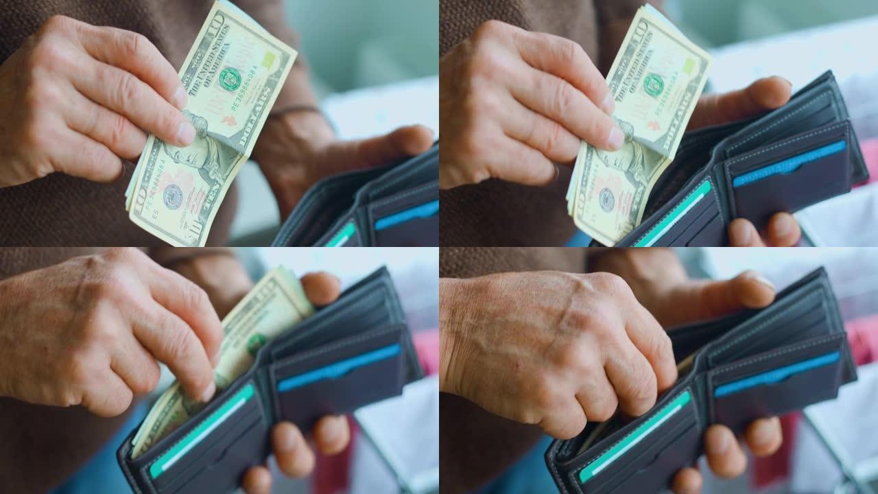 一个老人的手在他的钱包里加了美元钞票的特写镜头。