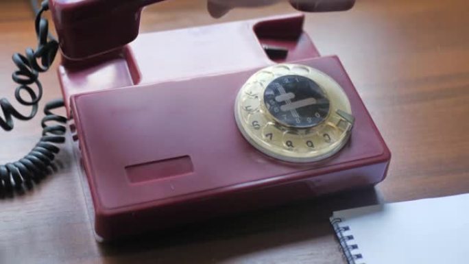 旧木桌上老式座机电话的特写。手是拨号号码，老式墙壁装饰