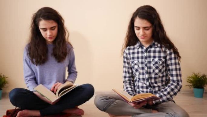 两个十几岁的女孩在家里的双胞胎姐妹坐在一起阅读带有真实纸页的书