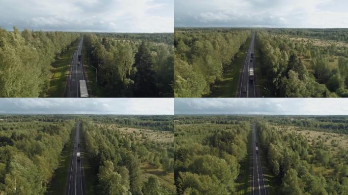 一条繁忙的高速公路，周围环绕着树木，卡车和汽车沿着这条高速公路行驶。汽车在狭窄的道路上超越了卡车。轨