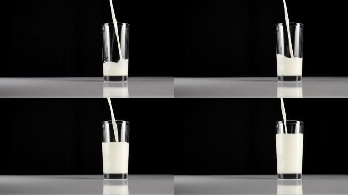 将新鲜的白色牛奶倒入黑色背景下的白色桌子上的透明玻璃杯中。呆在家里吃健康食物的概念。美味的早餐。宽镜