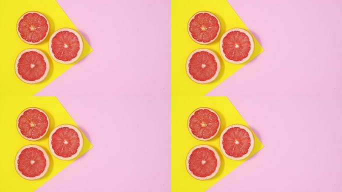 三个半红色葡萄柚出现在黄色柔和的粉红色主题上。停止运动平铺