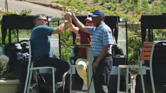 退休的男性高尔夫球手在阳光明媚的露台上练习推杆和喝啤酒