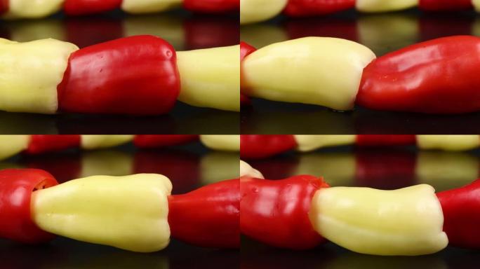 黑色背景上成排的甜黄色和红色辣椒。极值特写。健康食品概念。为沙拉准备蔬菜。循环运动。侧视图。旋转36