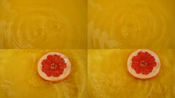 柚子片掉入橙色背景下的水中。慢动作。